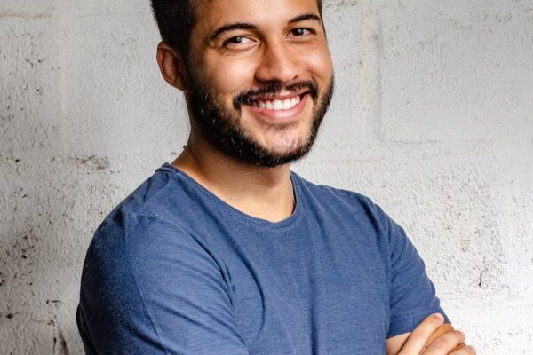 Your Energy is Everything portrait photo of smiling man with his arms crossed standing in front of a wall