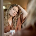 You’re Not Where You Want to Be a woman looking at her reflection while holding a ceramic mug